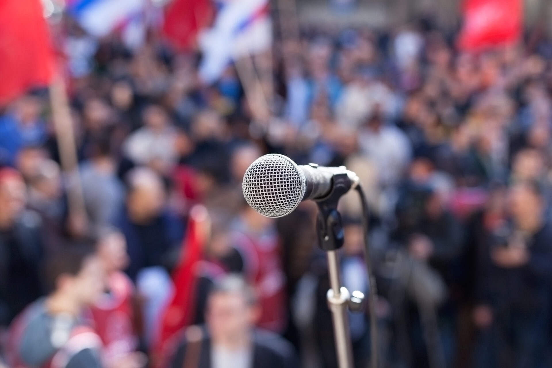 Protest.,Public,Demonstration.,Microphone,In,Focus,Against,Blurred,Audience.