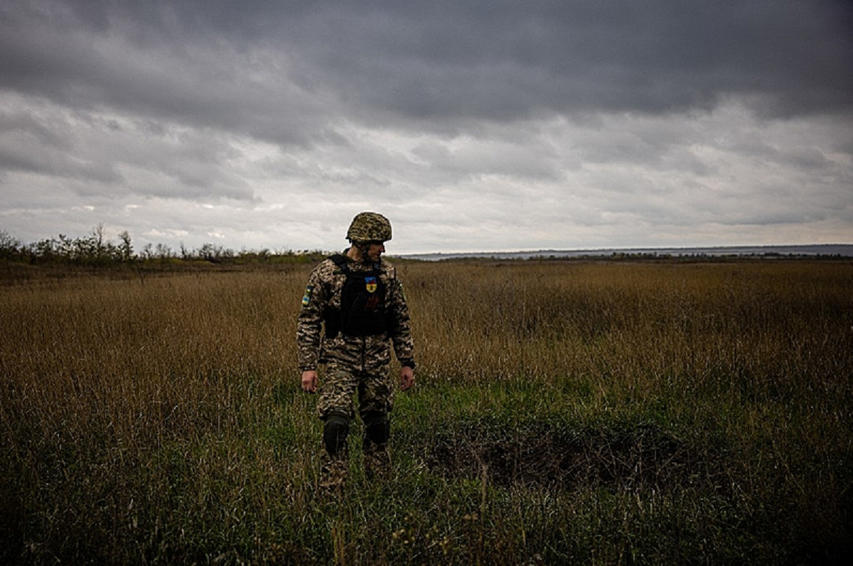 Um militar ucraniano ao lado de uma cratera de morteiro em um campo na região de Donetsk, no leste da Ucrânia, em 24 de outubro de 2022. - Dimitar Dilkoff / AFP
